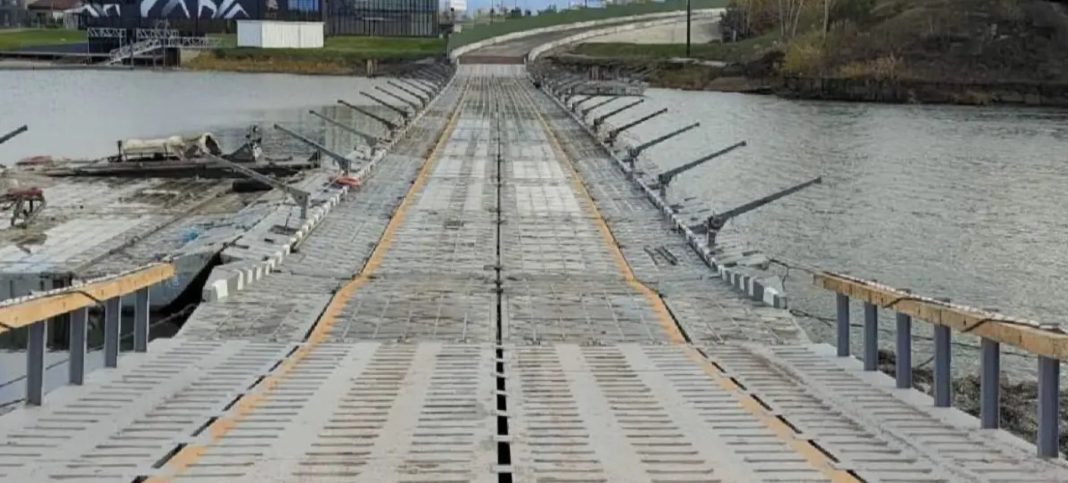 A temporary metal footbridge across a body of water with a road deck