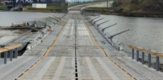 A temporary metal footbridge across a body of water with a road deck