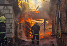 Two State Emergency Service firefighters are putting out a major fire in a damaged building engulfed in flames and thick smoke.