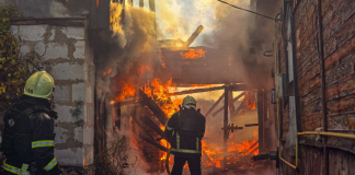 Two State Emergency Service firefighters are putting out a major fire in a damaged building engulfed in flames and thick smoke.