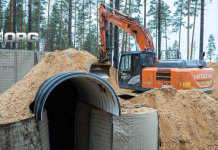 A Hitachi excavator is carrying out earthworks near the entrance to a defence bunker in a wooded area of Estonia as part of the construction of the Baltic Defence Belt