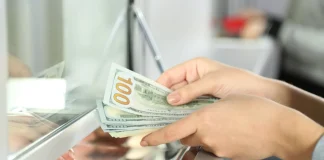 Долар наближається до 46 грн: скільки коштує в банках Жінка перераховує стодоларові банкноти біля касового вікна банку