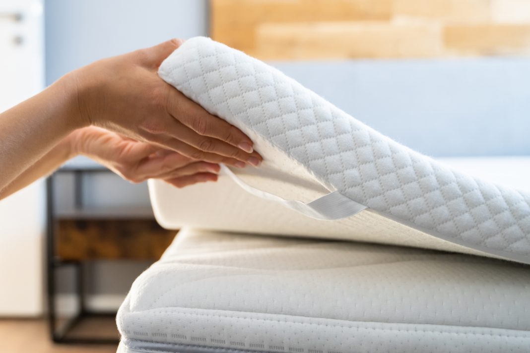 A mattress topper being placed on top A mattress topper to even out and soften the sleeping surface