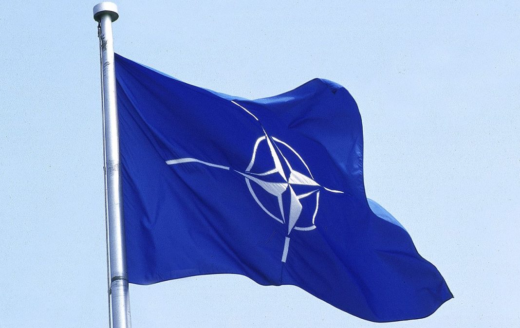 Прапор НАТО із символом Альянсу на тлі неба