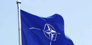 Прапор НАТО із символом Альянсу на тлі неба