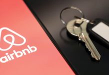 The Airbnb accommodation rental service logo on a smartphone screen, next to the keys to the property