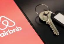 Логотип сервісу оренди житла Airbnb на екрані смартфона поруч із ключами від помешкання