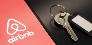 Логотип сервісу оренди житла Airbnb на екрані смартфона поруч із ключами від помешкання