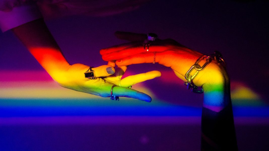 lgbtik A person’s hands, illuminated by the colours of the rainbow, symbolising LGBTIQ+ rights and equality.