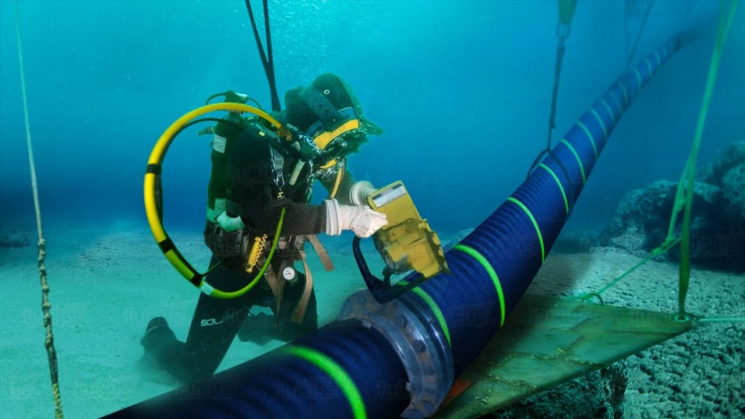 Underwater cables A diver is working on a large undersea telecommunications cable on the seabed