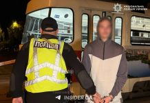 Поліцейський поруч із затриманим чоловіком біля трамвая в Києві