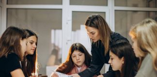 The teacher helps the schoolgirls work through the learning materials