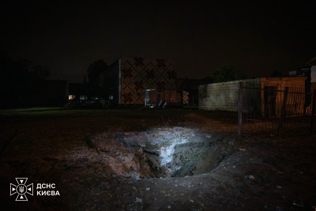 A large crater in the ground following the Russian shelling of Kyiv last night; emergency services are at the scene.