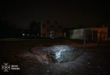 A large crater in the ground following the Russian shelling of Kyiv last night; emergency services are at the scene.