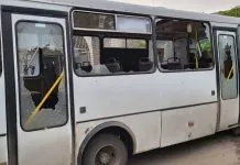 Білий міський автобус із вибитими вікнами та уламками скла на сидіннях у салоні
