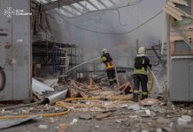 Rescue workers from the State Emergency Service are extinguishing a fire amongst the ruins of a warehouse in Sumy