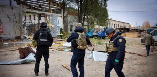 Поліцейські та рятувальник оглядають пошкоджені будівлі й уламки конструкцій після російських обстрілів Сумської області 28 жовтня 2026 року