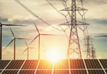 Solar panels, wind turbines and high-voltage pylons against the backdrop of the sunset