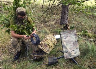 Конгресмени США закликали Пентагон розширити Starshield для України Український військовослужбовець у маскувальному спорядженні налаштовує кабель супутникового термінала Starlink у лісовій місцевості.
