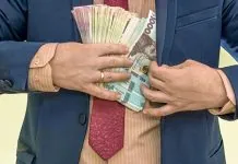 Чоловік у діловому костюмі тримає пачки українських гривень за пазухою, ілюструючи тему високих зарплат посадовців і бюджетних обмежень.