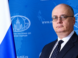 Гутерріш призначив росіянина відповідальним за розмінування в ООН Російський дипломат Гліб Десятников у діловому костюмі на тлі символіки Міністерства закордонних справ Росії та державного прапора РФ