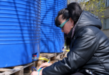 Water for just a few hours a day: what’s happening in Novoyavorivsk A woman is drawing water from a special container via a hose near the large blue drinking water tanks.