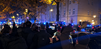 Нічне скупчення людей біля автомобілів із синіми проблисковими маячками